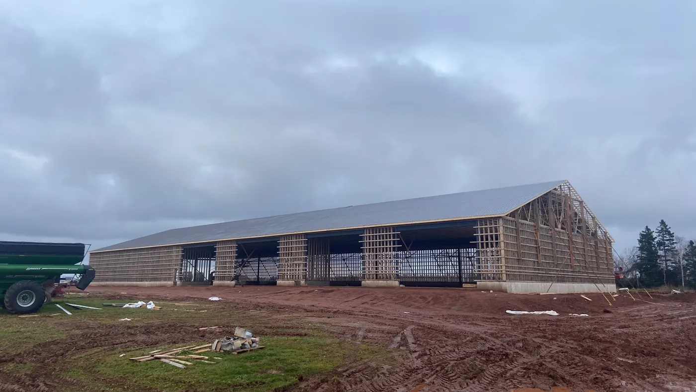 A long barn framed and roofed, trusses visible down its length