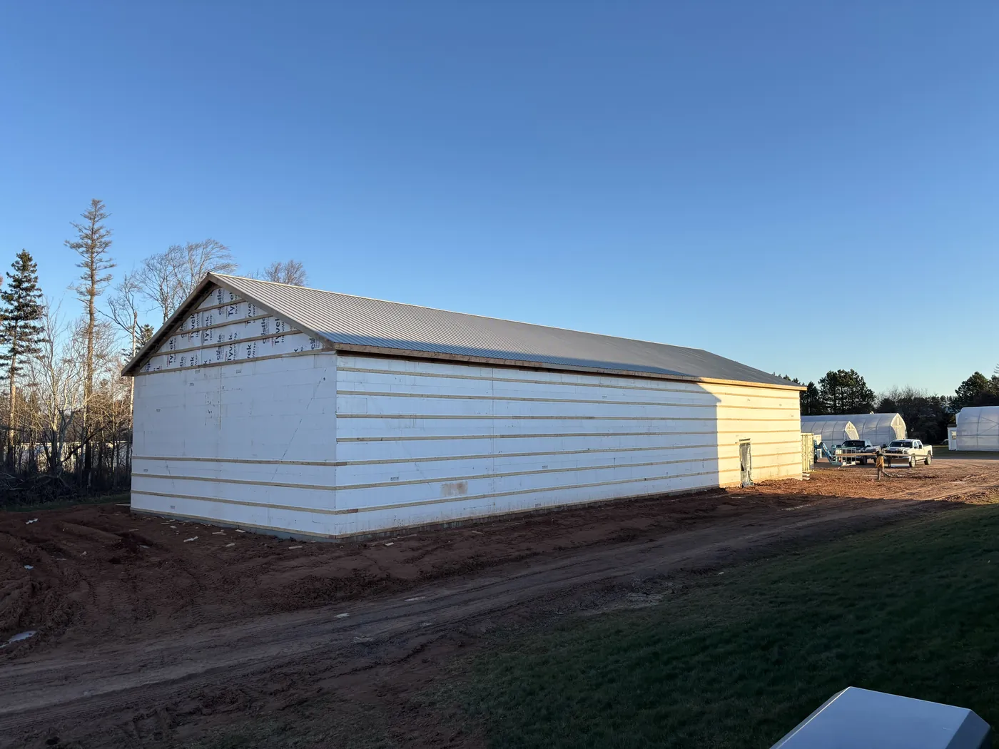 A finished white farm building in the evening sun